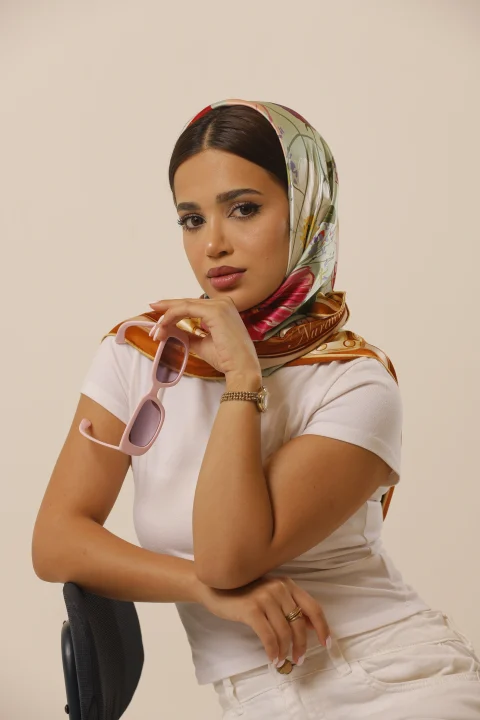 Meadow Poem silk scarf with colourful flowers and a golden border, worn as a headscarf