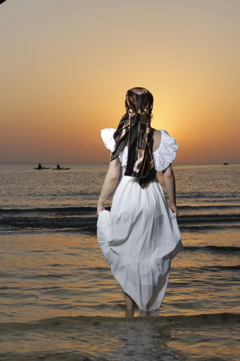 Wild Grace tied over the hair, seen from behind walking toward the sea at sunset